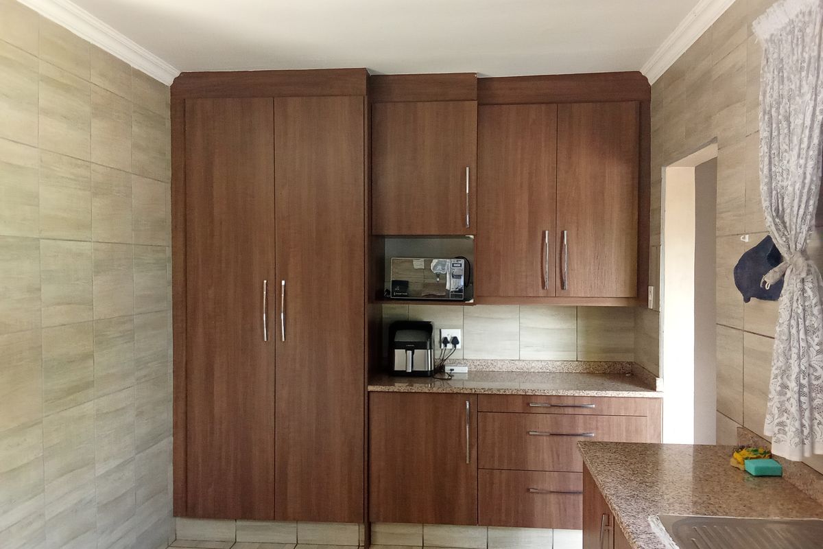 A functional kitchen featuring wood-finish cabinetry, granite countertops, and neutral wall tiling, providing ample storage and workspace.