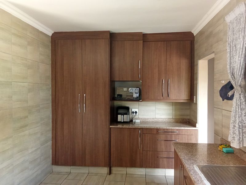 A functional kitchen featuring wood-finish cabinetry, granite countertops, and neutral wall tiling, providing ample storage and workspace.