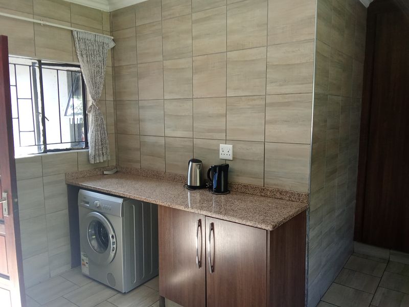 A functional laundry area featuring tiled walls, granite countertops, and built-in cabinetry, providing a clean and practical space for household utility tasks.