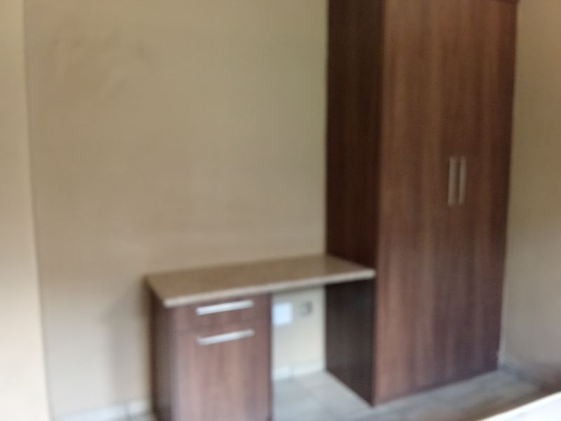 A bedroom featuring a built-in wooden wardrobe and a matching integrated desk unit.