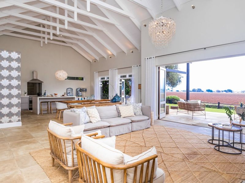 Spacious open-plan living area featuring a vaulted ceiling with exposed rafters, a modern kitchen island, and large sliding doors opening to a scenic outdoor view.