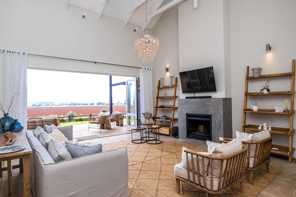Spacious living room featuring a vaulted ceiling, a modern concrete fireplace, and large sliding doors that open onto a patio with scenic views.