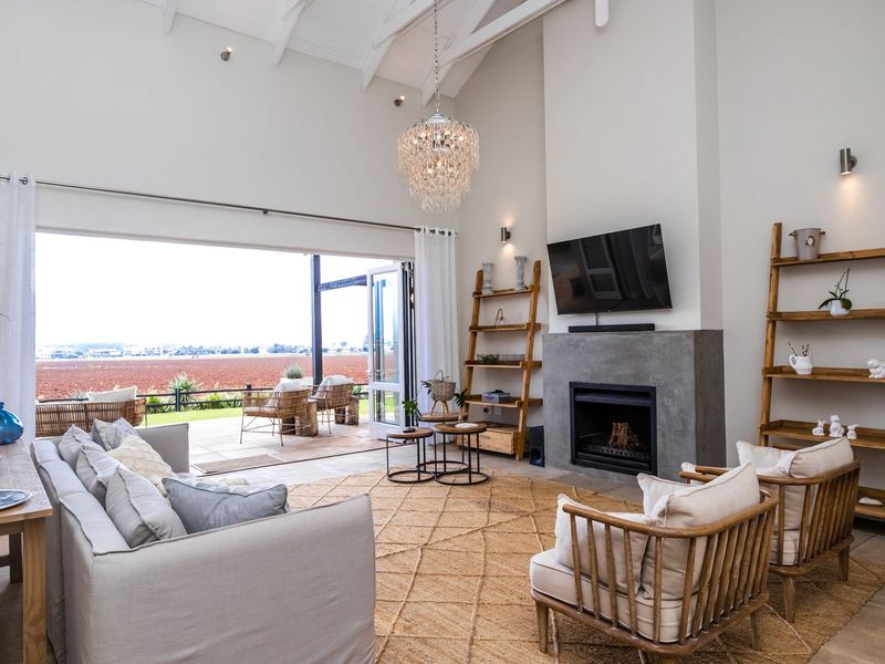 Spacious living room featuring a vaulted ceiling, a modern concrete fireplace, and large sliding doors that open onto a patio with scenic views.