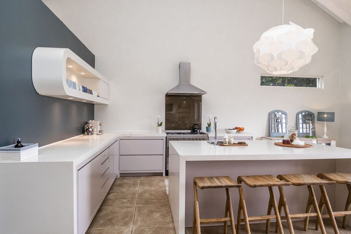 Modern kitchen featuring a large central island, stone countertops, sleek cabinetry, and a vaulted ceiling, creating a bright and spacious culinary environment.