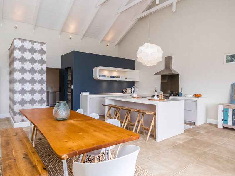 Spacious open-plan kitchen and dining area featuring a vaulted ceiling with exposed rafters, a central kitchen island, and modern cabinetry.