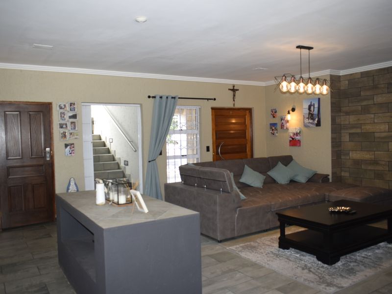 Spacious living area featuring a stone-cladding accent wall, modern pendant lighting, and direct access to an internal staircase.