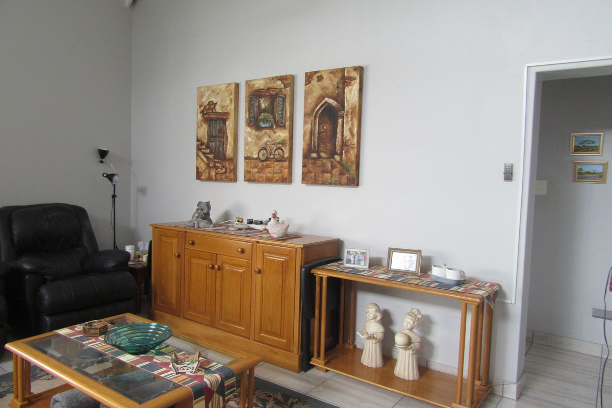 A living room area featuring tiled flooring, high ceilings, and neutral wall finishes, providing a functional and well-maintained space.