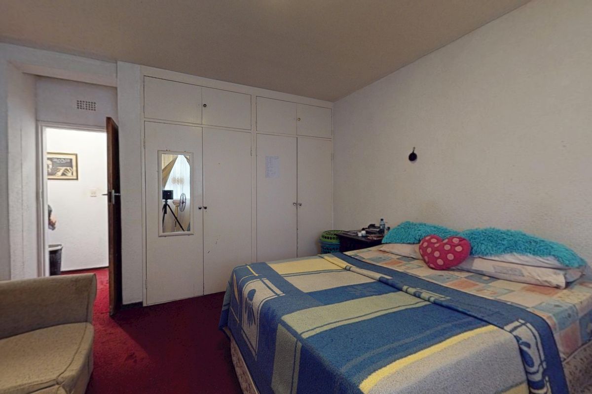 A bedroom featuring built-in cupboards and carpeted flooring, offering a functional space with potential for cosmetic updates.