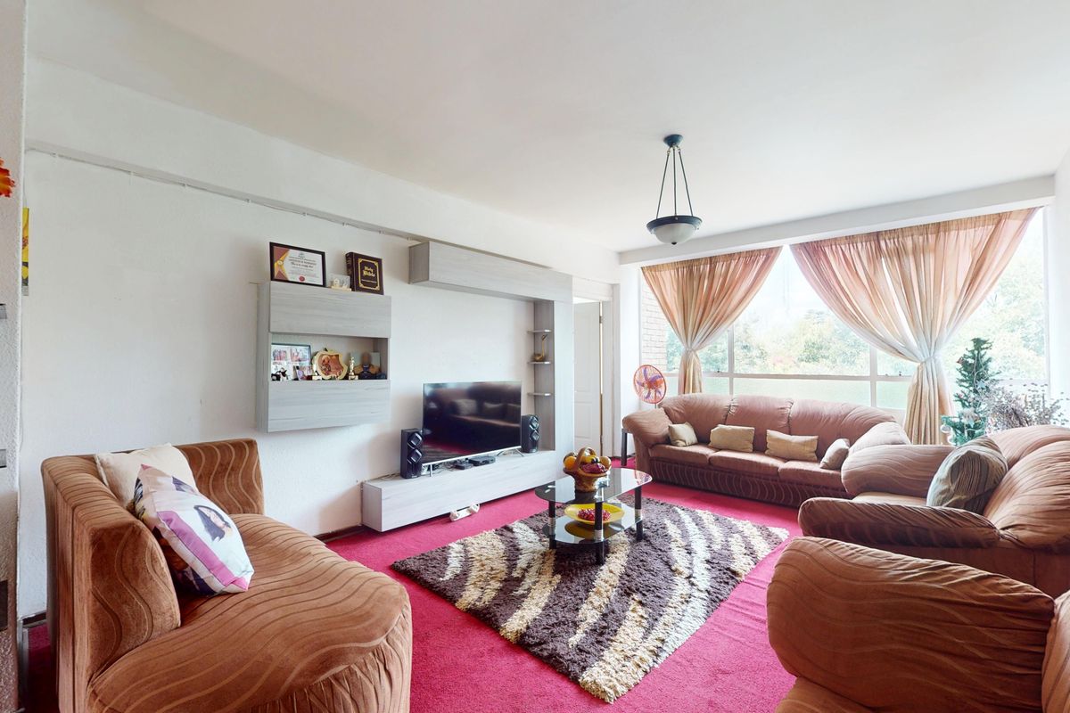 A spacious living room featuring a large window that provides ample natural light and a wall-mounted shelving unit for storage.