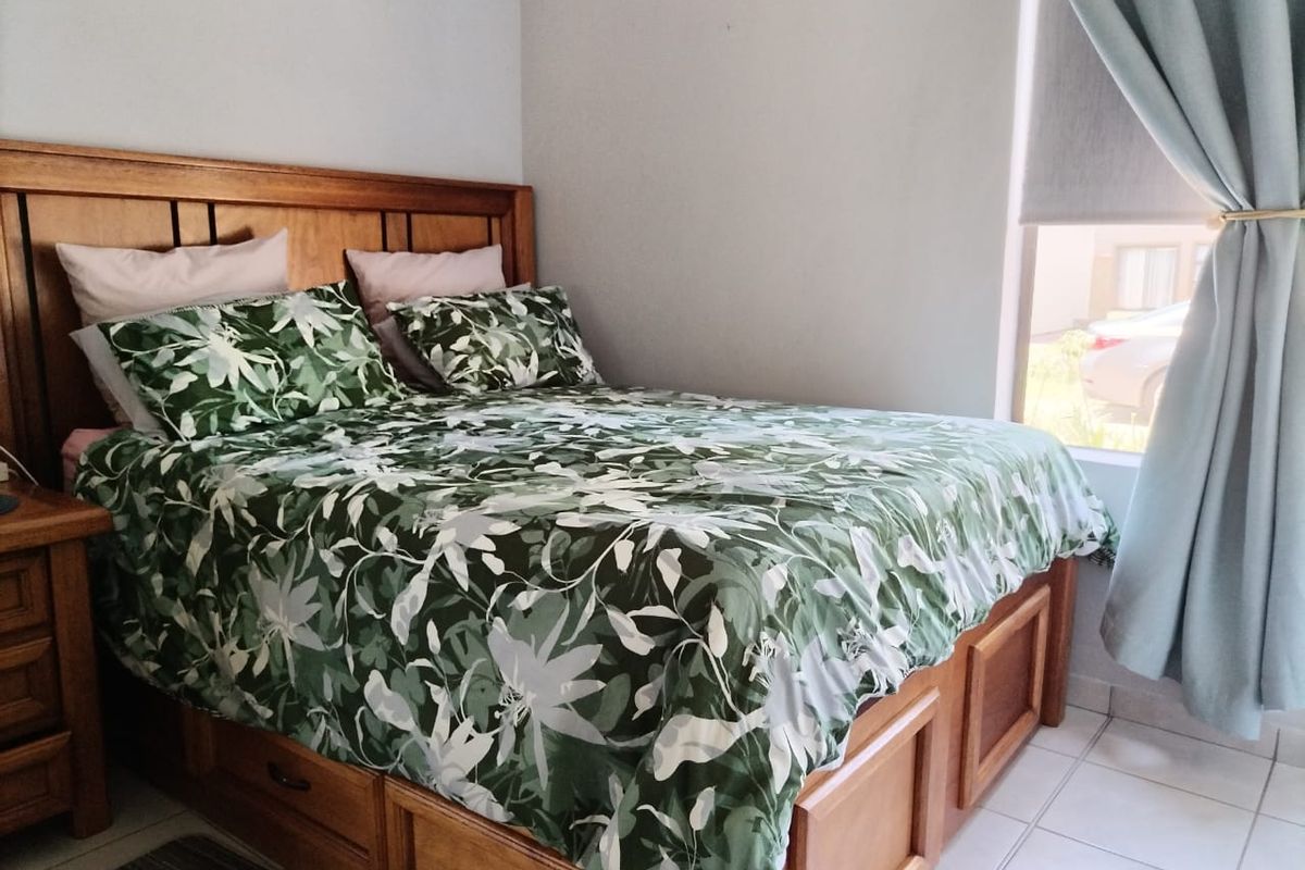 A bedroom featuring tiled flooring and a window with curtains, providing natural light.