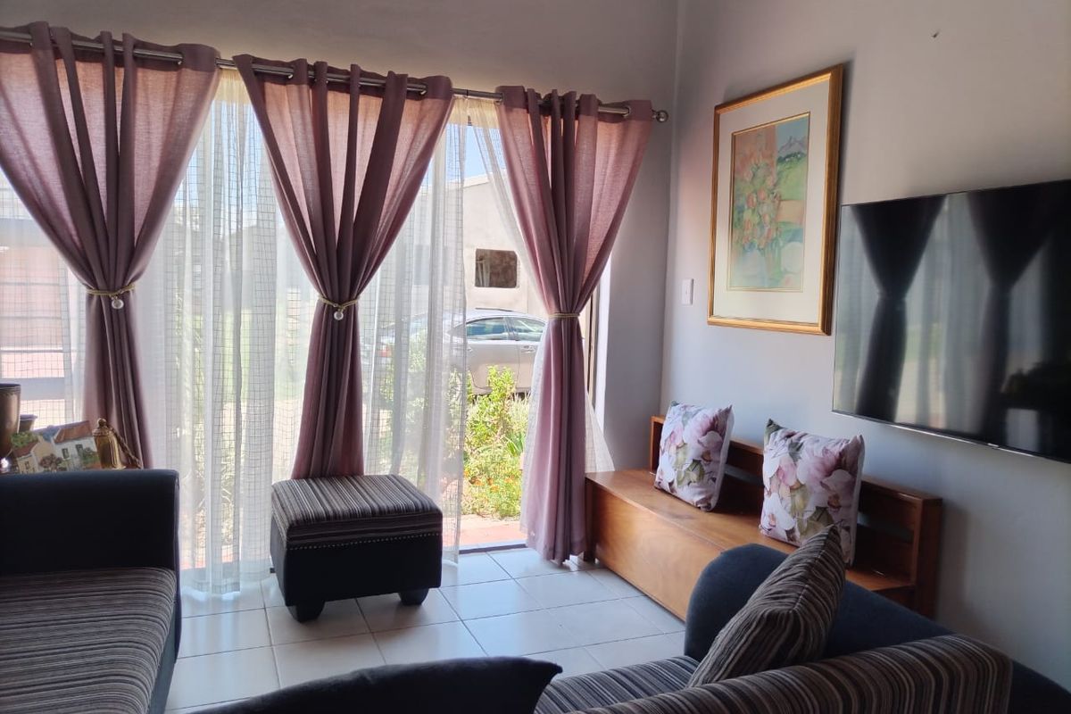 A comfortable living room featuring tiled flooring and a large sliding glass door that provides natural light and access to the outdoor area.