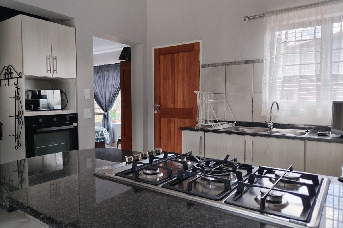 Functional kitchen featuring granite countertops, a built-in gas hob, integrated oven, and ample cabinetry, providing a practical workspace within the retirement village unit.