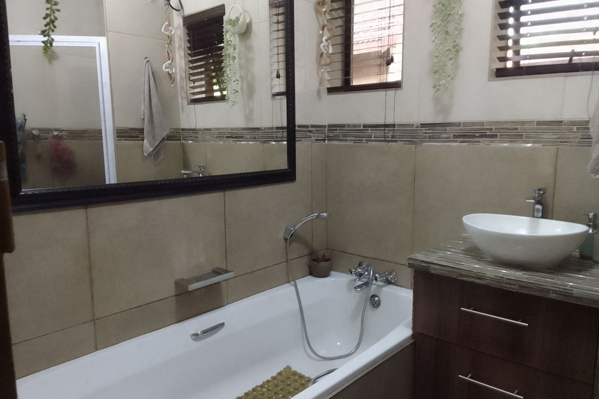 A well-maintained bathroom featuring a built-in bathtub, a modern vessel sink on a vanity cabinet, and tiled wall finishes.