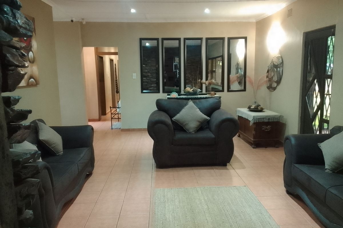 Spacious living room featuring tiled flooring, recessed downlighting, and wall sconces, providing a comfortable and well-lit area for relaxation.