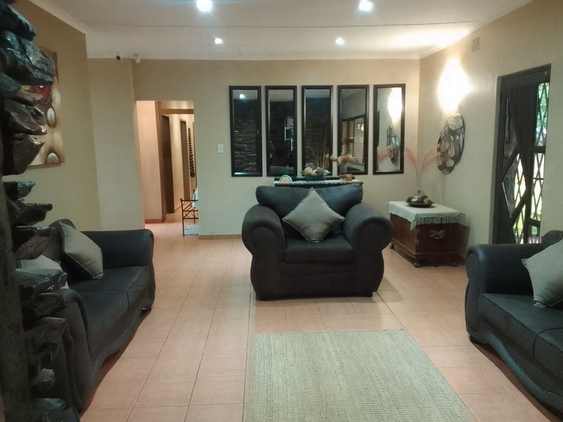 Spacious living room featuring tiled flooring, recessed downlighting, and wall sconces, providing a comfortable and well-lit area for relaxation.