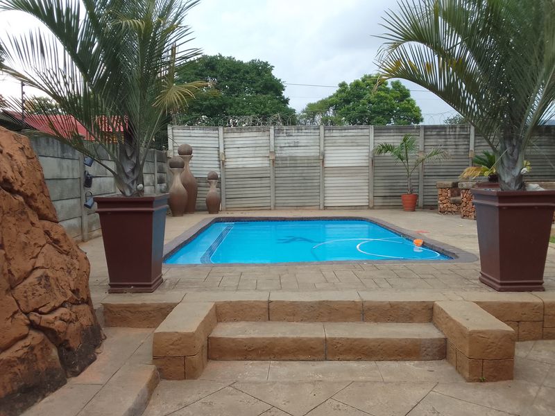 Outdoor pool area featuring a paved deck, built-in steps, and a precast concrete boundary wall, providing a private space for recreation.