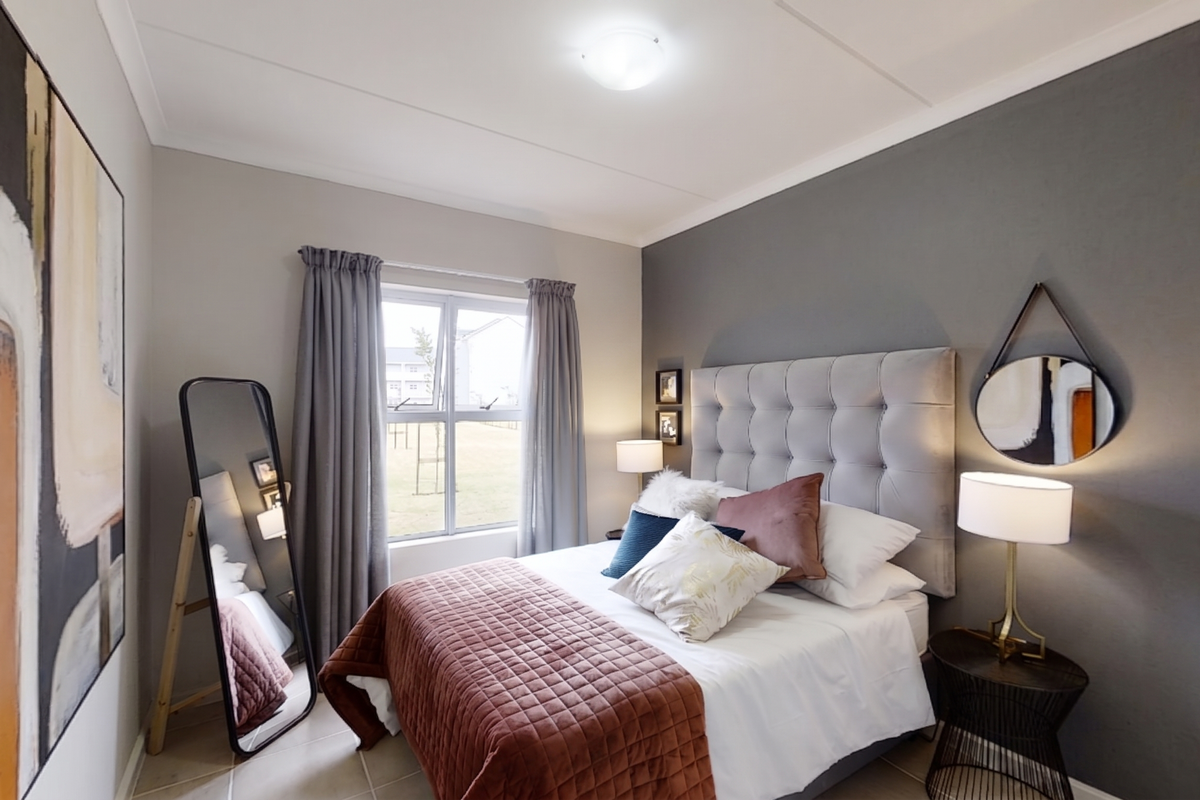 A well-maintained bedroom featuring neutral wall tones, a feature accent wall, tiled flooring, and a window providing natural light.