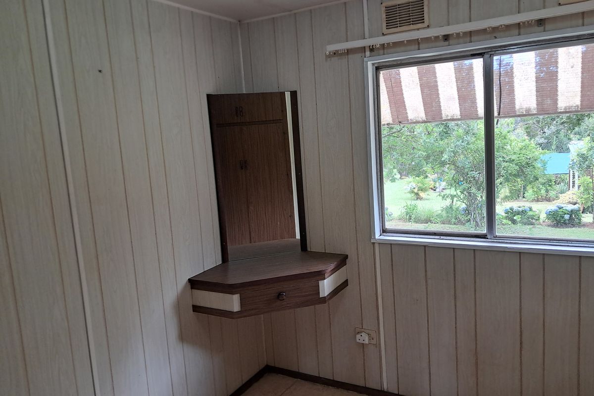 A bedroom featuring wood-look wall paneling, a built-in corner vanity unit, and a window overlooking the garden.