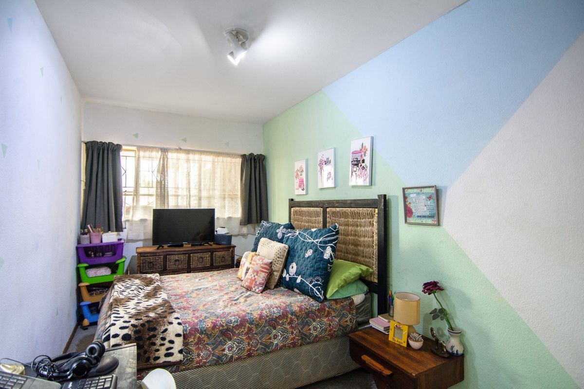 A standard bedroom featuring a window with security bars and a ceiling-mounted spotlight fixture.