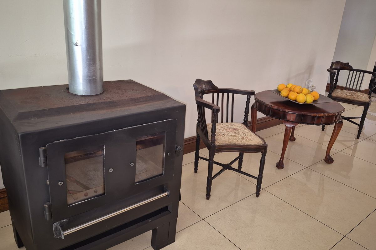 A living area featuring a freestanding fireplace with a metal flue and polished tiled flooring.
