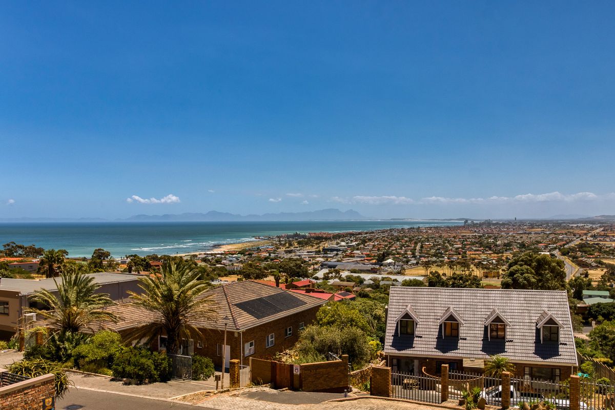 Elevated coastal view overlooking the surrounding residential neighbourhood, coastline, and distant mountain range.