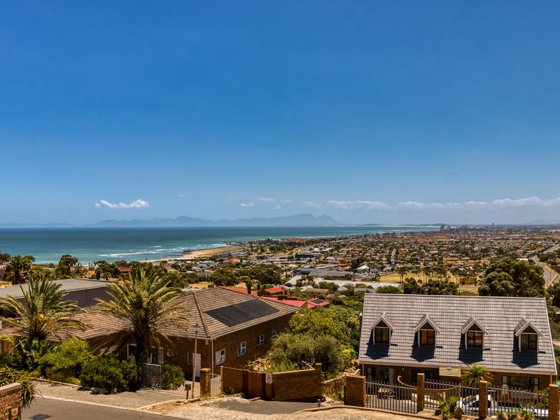 Elevated coastal view overlooking the surrounding residential neighbourhood, coastline, and distant mountain range.