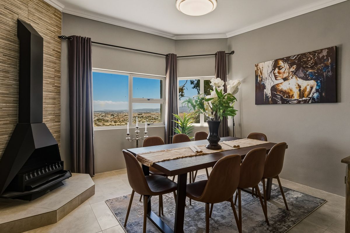 A well-appointed dining room featuring a modern freestanding fireplace, tiled flooring, and large windows offering expansive views.