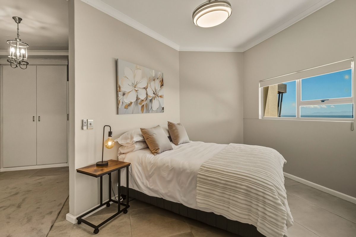 A well-maintained bedroom featuring tiled flooring, a built-in wardrobe, and a window offering natural light and views.