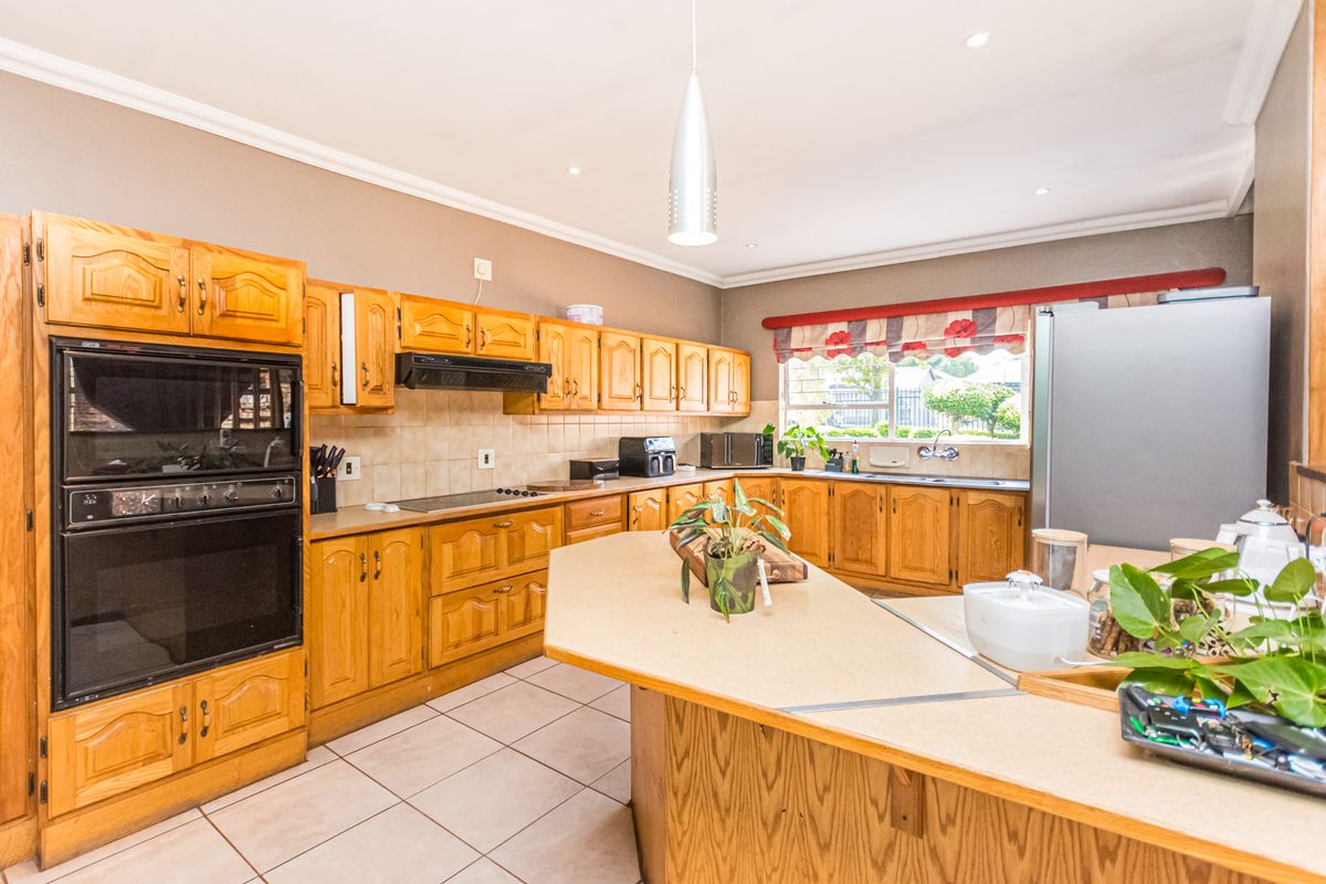 Spacious kitchen featuring traditional wooden cabinetry, laminate countertops, built-in double oven, and tiled flooring, offering a functional layout with ample storage space.