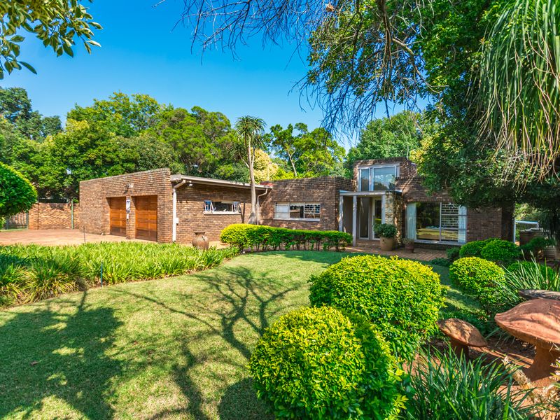 A well-maintained single-story brick house featuring a double garage, established garden, and paved driveway, showcasing classic architectural character.