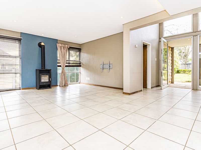 Spacious living area featuring tiled flooring, a freestanding fireplace, and large glass doors providing direct access to the outdoor garden space.