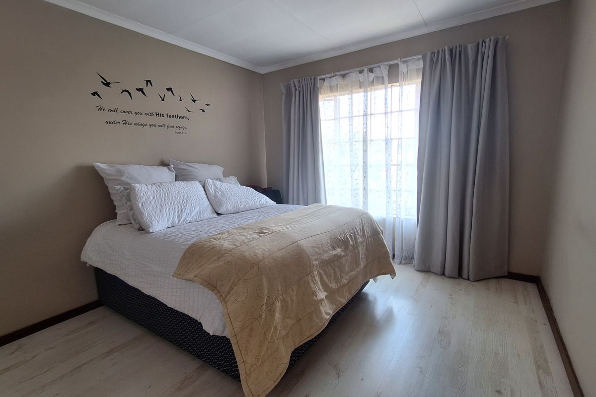 A bedroom featuring light-toned laminate flooring and neutral wall paint, providing a clean and functional space.