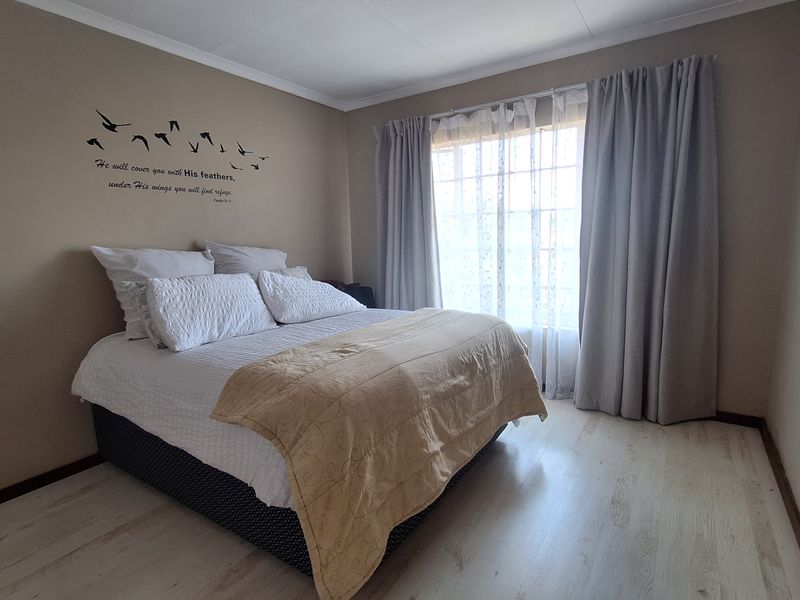 A bedroom featuring light-toned laminate flooring and neutral wall paint, providing a clean and functional space.
