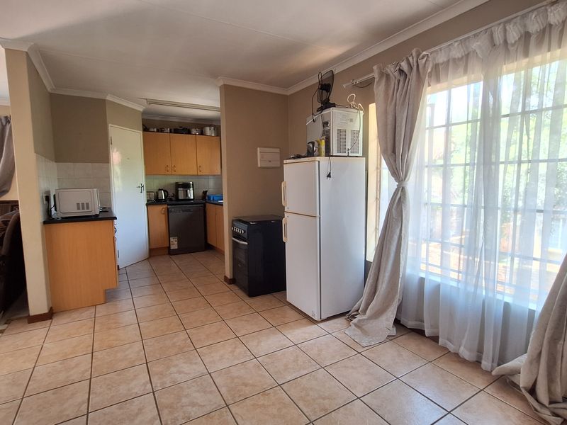 Open plan kitchen and living area featuring tiled flooring, built-in cabinetry, and a large window allowing for natural light.