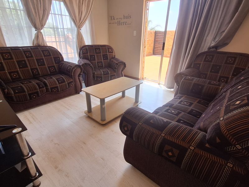 A living room featuring light-toned laminate flooring and a sliding glass door providing access to an outdoor patio area.