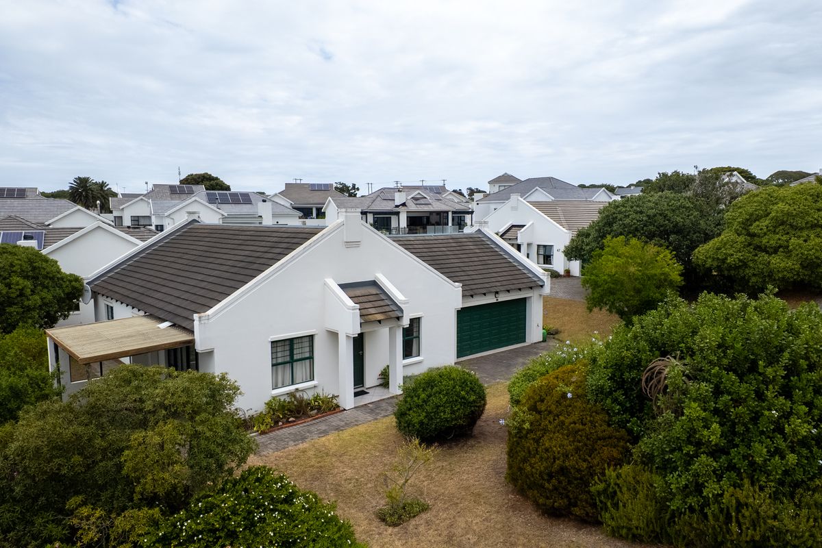 Aerial view of a residential property featuring a tiled roof, integrated garage, and a covered patio set within a landscaped suburban estate.