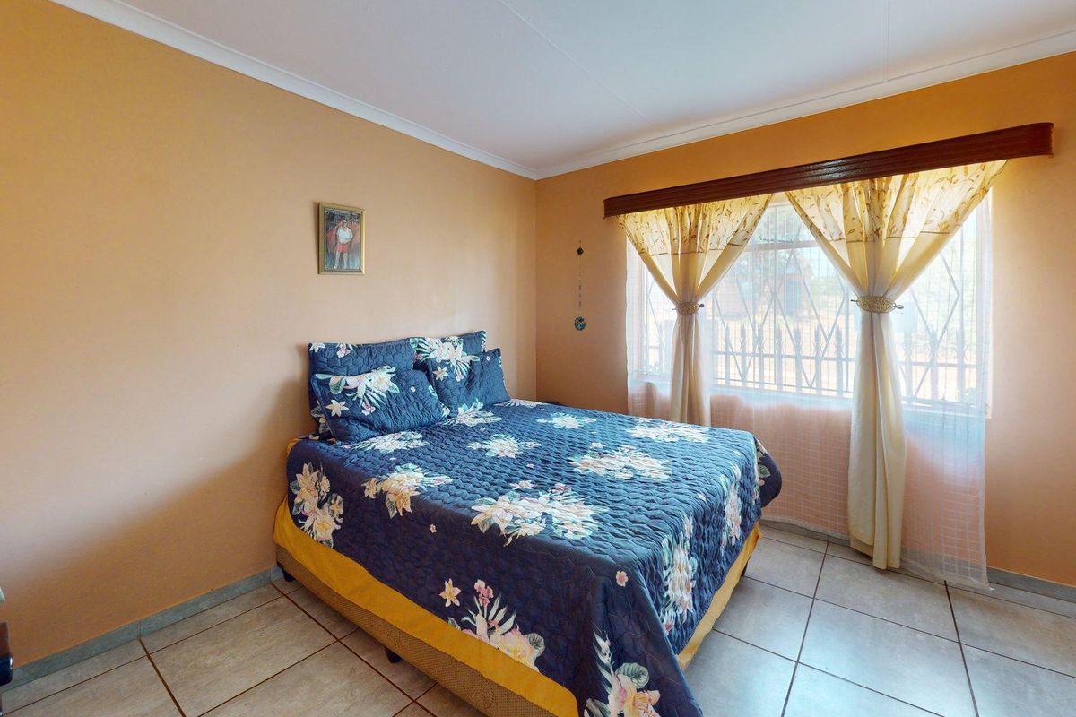 A standard bedroom featuring tiled flooring, security bars on the window, and neutral wall finishes.