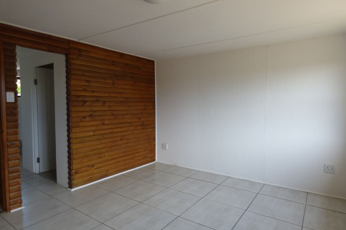 An empty living area featuring neutral floor tiles and a distinctive timber log feature wall, providing a clean canvas for interior design.