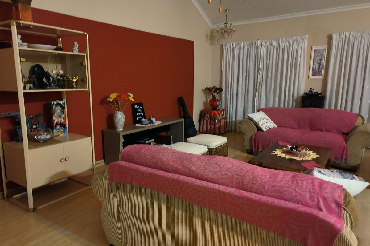 A living room featuring vaulted ceilings and laminate flooring, providing a spacious area with potential for modern updates.