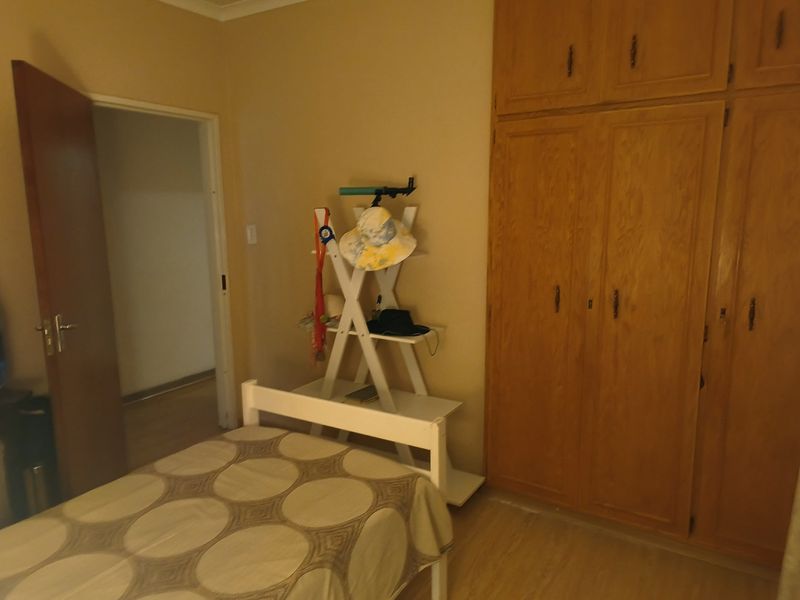A bedroom featuring built-in wooden cupboards and laminate flooring, providing functional storage and a neutral base for interior updates.