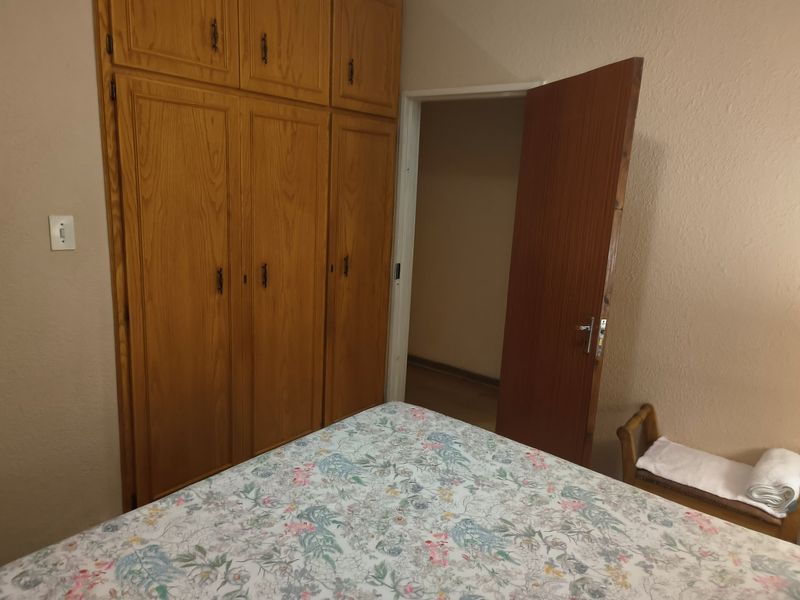 A bedroom featuring built-in wooden cupboards and a wooden door, offering functional storage space.