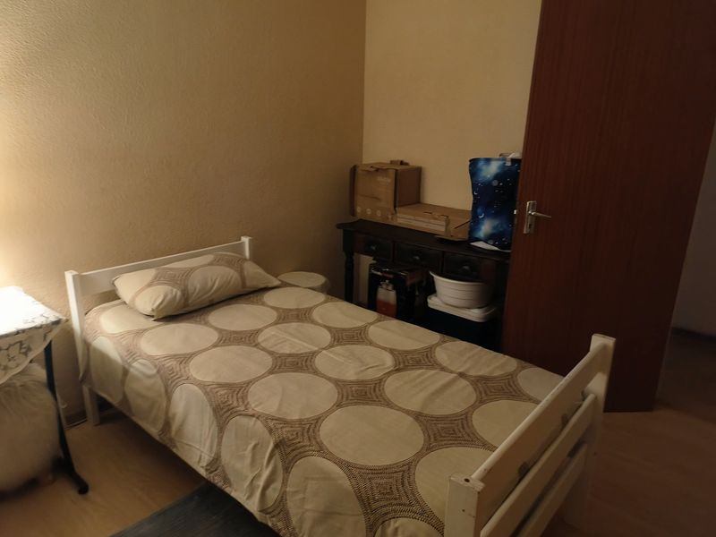 A simple bedroom featuring laminate flooring and a solid core door, providing a functional space for rest.