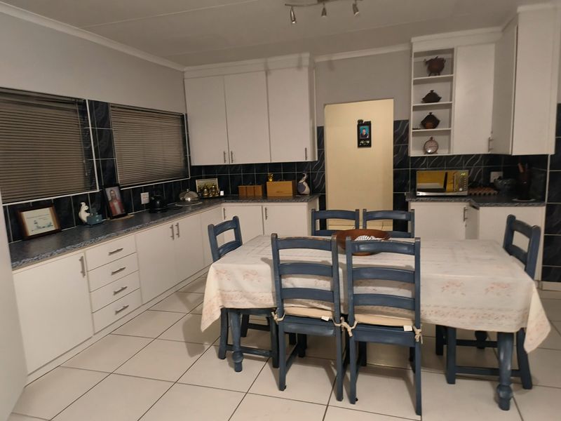 Open plan kitchen and dining area featuring white cabinetry, tiled backsplash, and tiled flooring, providing a functional space for cooking and dining.