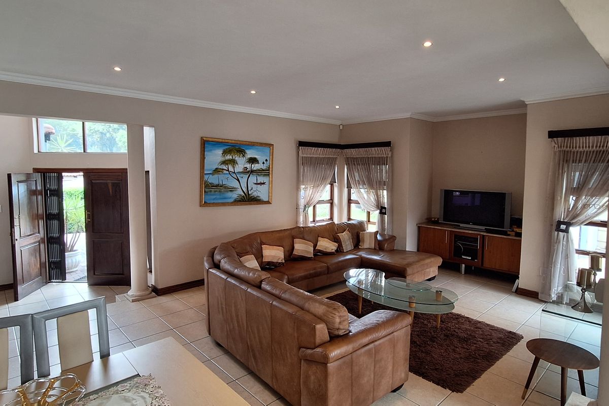 Spacious living room featuring ceramic tiled flooring, recessed downlighting, and structural columns, providing an open and well-lit area for relaxation.
