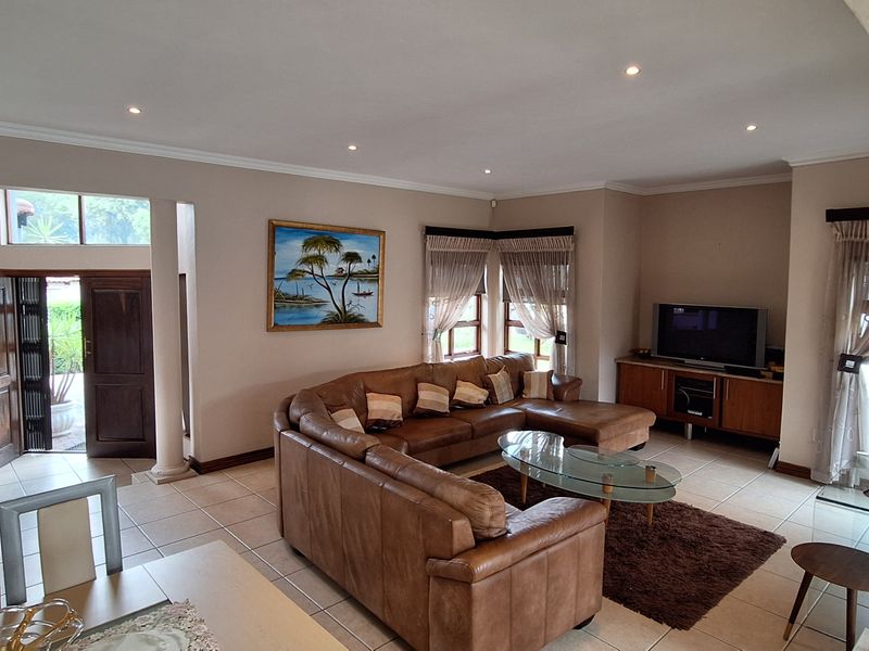 Spacious living room featuring ceramic tiled flooring, recessed downlighting, and structural columns, providing an open and well-lit area for relaxation.