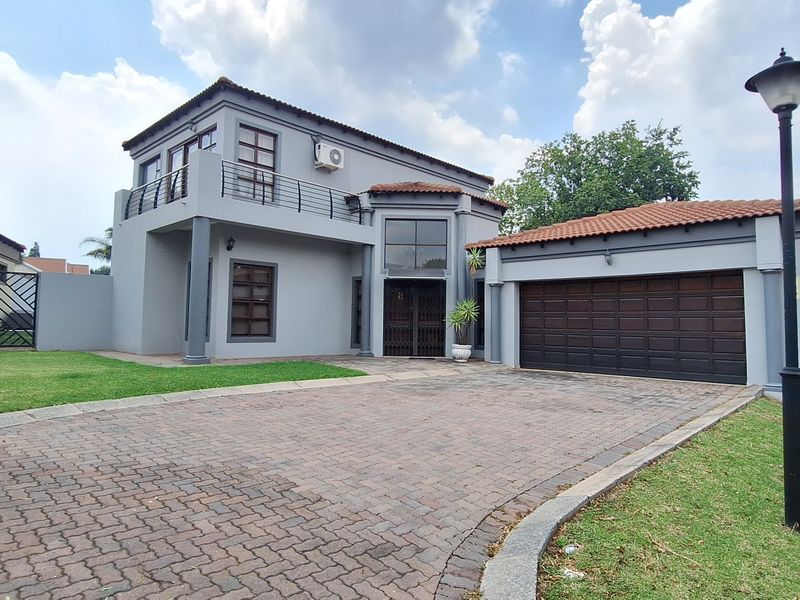 Front elevation of a double-story house featuring a paved driveway, double garage, and an upper-level balcony.
