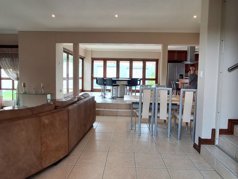 Spacious open-plan living and dining area featuring tiled floors, recessed lighting, and direct access to the rear patio through timber bi-fold doors.