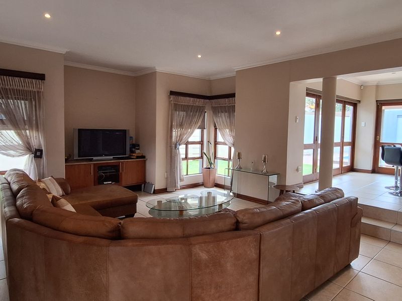 Spacious open-plan living and dining area featuring tiled floors, recessed lighting, and large timber-framed glass doors leading to the exterior.