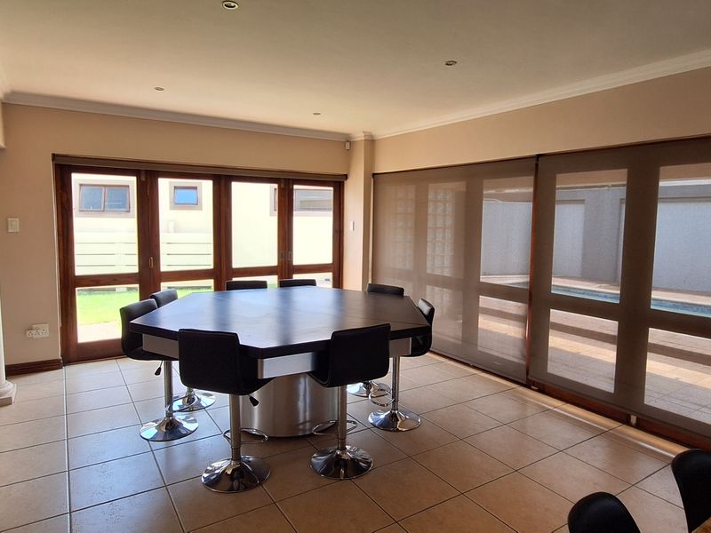 Spacious open-plan living and dining area featuring tiled floors, recessed lighting, and large sliding glass doors providing direct access to the outdoor pool area.