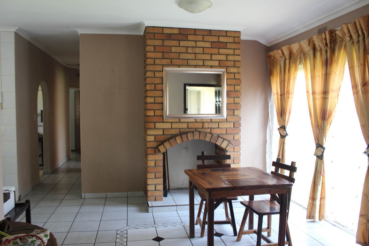 Living room featuring a prominent brick fireplace, ceramic tiled flooring, and sliding glass doors providing natural light.